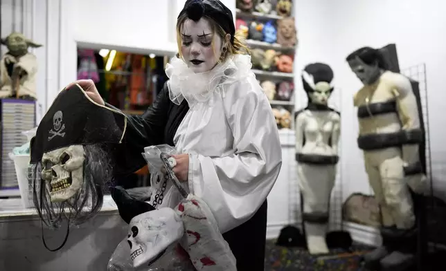 Olive Luther prepares to stock costume displays at The Theatrical Shop, Tuesday, Oct. 29, 2024, in West Des Moines, Iowa. (AP Photo/Charlie Neibergall)