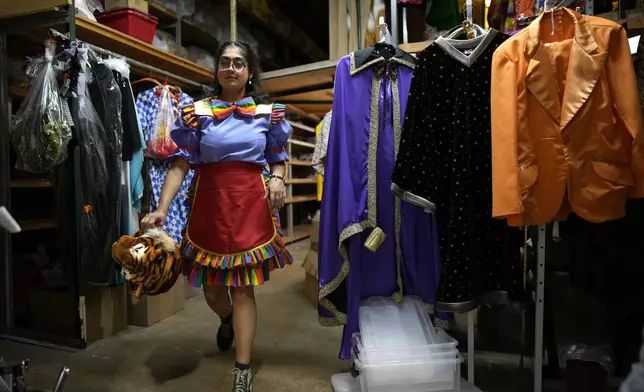 Hamida Mokhtar walks past costumes in the storeroom at The Theatrical Shop, Tuesday, Oct. 29, 2024, in West Des Moines, Iowa. (AP Photo/Charlie Neibergall)