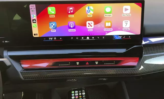 This photo provided by Edmunds shows an Apple iPhone connected wirelessly to a BMW i5 through an Apple CarPlay interface. The iPhone is also placed on a wireless charging pad. (Courtesy of Edmunds via AP)