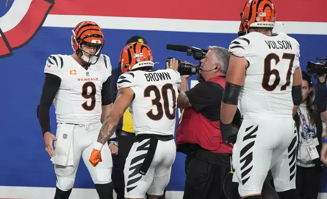 Cincinnati Bengals quarterback Joe Burrow (9) celebrates with running back Chase Brown (30) and guard Cordell Volson (67) after scoring a touchdown during the first half of an NFL football game against the New York Giants, Sunday, Oct. 13, 2024, in East Rutherford, N.J. (AP Photo/Frank Franklin II)