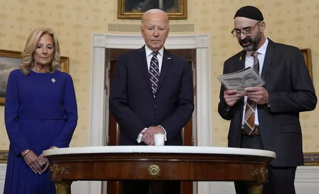 President Joe Biden, center, standing with first lady Jill Biden, left, and Rabbi Aaron Alexander of the Adas Israel Congregation, participates in a memorial candle-lighting in the Blue Room of the White House in Washington, Monday, Oct. 7, 2024, to mark the one-year anniversary of the Hamas attack on Israel that left about 1,200 people dead. (AP Photo/Susan Walsh)