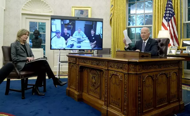 President Joe Biden, right, and White House Homeland Security Advisor Liz Sherwood-Randall, left, speak with North Carolina Gov. Roy Cooper, on screen at center right, and Administrator of the U.S. Federal Emergency Management Agency Deanne Criswell, onscreen at center left, about the Biden administration's efforts to aid in recovery from the aftermath of Hurricane Helene from the Oval Office of the White House in Washington, Monday, Sept. 30, 2024. (AP Photo/Mark Schiefelbein)