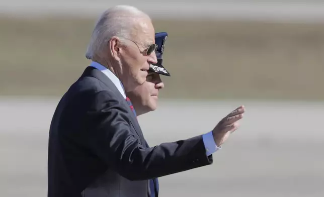 President Joe Biden, left, is escorted by Col. Paul Pawluk, Vice Commander, 89th Airlift Wing, right, as he walks from Marine One before boarding Air Force One at Joint Base Andrews, Md., Tuesday, Oct. 22, 2024. (AP Photo/Luis M. Alvarez)