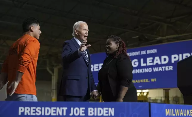 President Joe Biden, standing with Alonso Romo, LiUNA Local 113 &amp; introducer, left, and Shy McElroy, advocate &amp; introducer, right, waves to the audience after speaking at an event at the Milwaukee Department of Public Works in Milwaukee, Tuesday, Oct. 8, 2024, to discuss his administration's progress in replacing lead pipes in Wisconsin and across the country. (AP Photo/Susan Walsh)