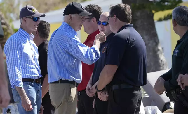 President Joe Biden, second left, joined by Sen. Rick Scott, R-Fla., left, speaks with residents and federal, state, and local officials in St. Pete Beach, Fla., during a tour of areas affected by Hurricane Milton, Sunday, Oct. 13, 2024. (AP Photo/Manuel Balce Ceneta)