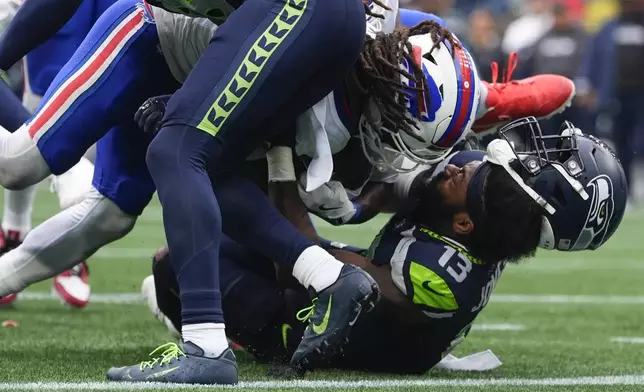 Seattle Seahawks linebacker Ernest Jones IV (13) has his helmet come off as Buffalo Bills running back James Cook (4) scores a touchdown during the second half of an NFL football game, Sunday, Oct. 27, 2024, in Seattle. (AP Photo/Lindsey Wasson)