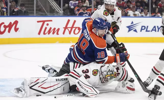 Chicago Blackhawks' goalie Petr Mrazek (34) makes the save on Edmonton Oilers' Zach Hyman (18) as Seth Jones (4) defends during the second period of an NHL hockey game in Edmonton, Alberta, Saturday, Oct. 12, 2024. (Jason Franson/The Canadian Press via AP)