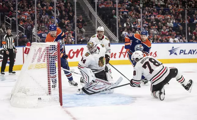 Chicago Blackhawks goalie Petr Mrazek (34) is scored on by Edmonton Oilers' Corey Perry, left, as T.J. Brodie (78) tries to defend during the second period of an NHL hockey game in Edmonton, Alberta, Saturday, Oct. 12, 2024. (Jason Franson/The Canadian Press via AP)