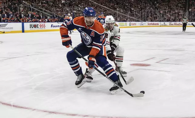 Chicago Blackhawks' Joey Anderson (22) and Edmonton Oilers' Darnell Nurse (25) battle for the puck during the first period of an NHL hockey game, Saturday, Oct. 12, 2024 in Edmonton, Alberta. (Jason Franson/The Canadian Press via AP)