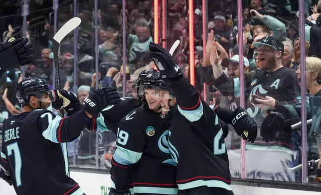 Seattle Kraken defenseman Vince Dunn, right, celebrates his goal with left wing Jared McCann (19) and right wing Jordan Eberle (7) during the second period of an NHL hockey game Tuesday, Oct. 8, 2024, in Seattle. (AP Photo/Lindsey Wasson)