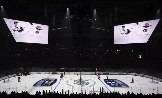 Seattle Kraken and St. Louis Blues players stand for a moment of silence for Columbus Blue Jackets player Johnny Gaudreau and his brother Matthew Gaudreau, who were killed by a driver in New Jersey in August, before an NHL hockey game, Tuesday, Oct. 8, 2024, in Seattle. (AP Photo/Lindsey Wasson)