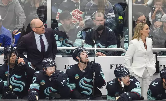 Seattle Kraken head coach Dan Bylsma, left back, and assistant coach Jessica Campbell, right back, look on during the first period of an NHL hockey game against the St. Louis Blues, Tuesday, Oct. 8, 2024, in Seattle. (AP Photo/Lindsey Wasson)