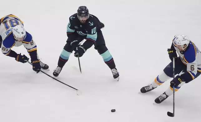 Seattle Kraken center Matty Beniers (10) looks on with St. Louis Blues center Dylan Holloway (81) as defenseman Philip Broberg (6) receives the puck during the first period of an NHL hockey game Tuesday, Oct. 8, 2024, in Seattle. (AP Photo/Lindsey Wasson)