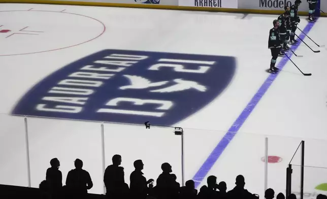 Seattle Kraken players stand for a moment of silence for Columbus Blue Jackets player Johnny Gaudreau and his brother Matthew Gaudreau, who were killed by a driver in New Jersey in August, before an NHL hockey game against the St. Louis Blues, Tuesday, Oct. 8, 2024, in Seattle. (AP Photo/Lindsey Wasson)