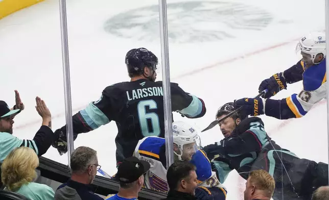 Seattle Kraken defenseman Adam Larsson (6) looks back as right wing Oliver Bjorkstrand (22) falls in a collision with St. Louis Blues left wing Nathan Walker (26) and right wing Alexey Toropchenko (13) during the first period of an NHL hockey game Tuesday, Oct. 8, 2024, in Seattle. (AP Photo/Lindsey Wasson)