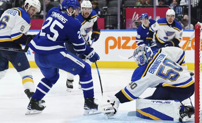 St. Louis Blues goaltender Jordan Binnington (50) stops Toronto Maple Leafs defenseman Conor Timmins (25) during second-period NHL hockey game action in Toronto, Thursday, Oct. 24, 2024. (Nathan Denette/The Canadian Press via AP)