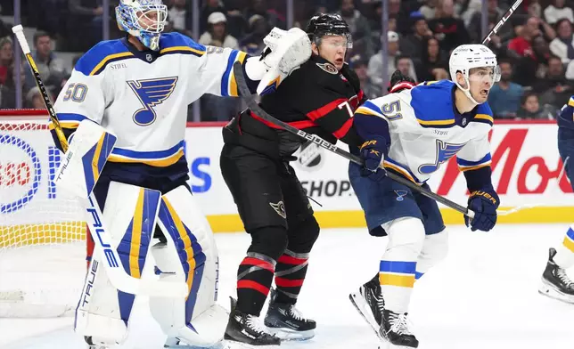 St. Louis Blues goaltender Jordan Binnington (50) gives Ottawa Senators left wing Brady Tkachuk (7) a shove as he fights for space in front of the net against Blues defenseman Matthew Kessel (51) during the second period of an NHL hockey game in Ottawa, Ontario, Tuesday, Oct. 29, 2024. (Sean Kilpatrick/The Canadian Press via AP)