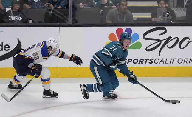 St. Louis Blues left wing Jake Neighbours, left, chases after San Jose Sharks center Macklin Celebrini, right, during the first period of an NHL hockey game Thursday, Oct. 10, 2024, in San Jose, Calif. (AP Photo/Godofredo A. Vásquez)