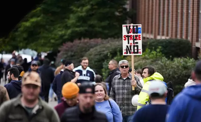 A worker holds a picket sign as Boeing employees vote on a new contract offer from the company, Wednesday, Oct. 23, 2024, at a voting location in the Angel of the Winds Arena in Everett, Wash. (AP Photo/Lindsey Wasson)