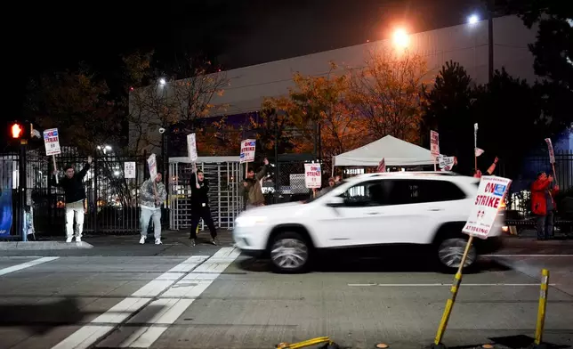 Boeing employees cheer and wave picket signs as a driver honks in support after a majority of union members voted to reject a new contract offer from the company, Wednesday, Oct. 23, 2024, in Renton, Wash. (AP Photo/Lindsey Wasson)