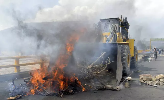 Police clears the fire barricades with a tractor as supporters of former Bolivian President Evo Morales block roads to pressure against him being prosecuted over allegations of minor abuse, near Cochabamba, Bolivia, Friday, Oct. 25, 2024. (AP Photo/Daniel Cartagena)