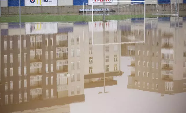 Apartment buildings are reflected at a flooded soccer field after a heavy rain in the village of Kiseljak, northern Bosnia, Friday, Oct. 4, 2024. (AP Photo/Armin Durgut)