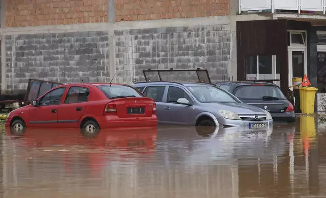 Vehicles are partially submerged in flood waters outside an apartment building in the village of Kiseljak, northern Bosnia, Friday, Oct. 4, 2024. (AP Photo/Armin Durgut)