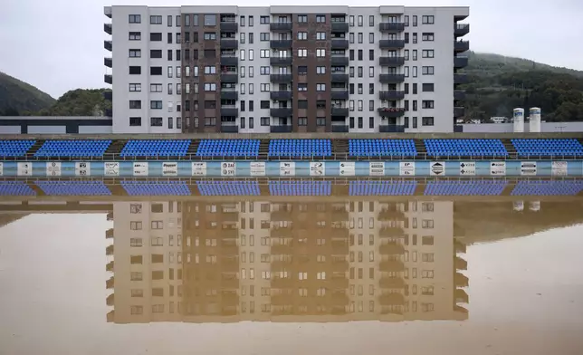 Apartment buildings are reflected at a flooded soccer field after a heavy rain in the village of Kiseljak, northern Bosnia, Friday, Oct. 4, 2024. (AP Photo/Armin Durgut)