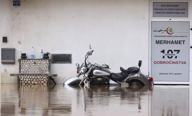 A motorcycle is partially submerged in flood waters outside an apartment building in the village of Kiseljak, northern Bosnia, Friday, Oct. 4, 2024. (AP Photo/Armin Durgut)