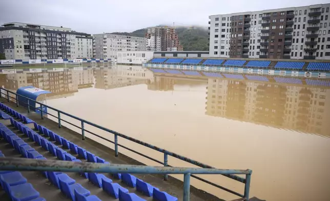 Apartment buildings are reflected at a flooded soccer field after a heavy rain in the village of Kiseljak, northern Bosnia, Friday, Oct. 4, 2024. (AP Photo/Armin Durgut)