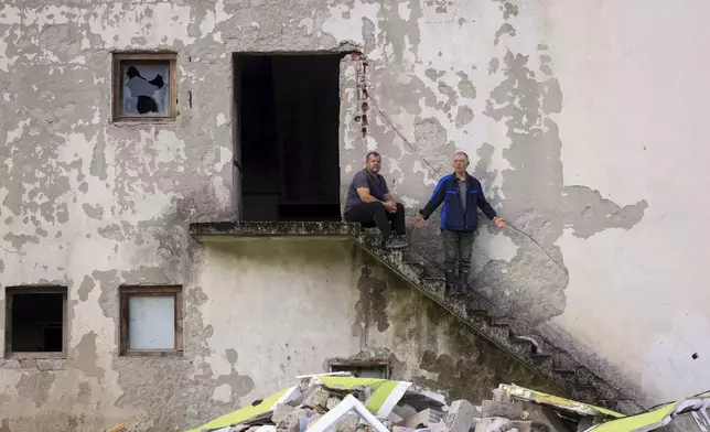 Men stand in despair in front of their destroyed house following a flooding in Buturovic Polje, Bosnia, Sunday, Oct. 6, 2024. (AP Photo/Armin Durgut)