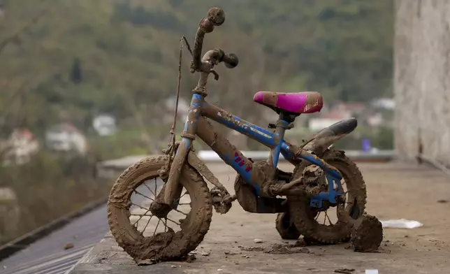 A children's bicycle is seen covered in mud following flash floods and landslides in Donja Jablanica, Bosnia, Thursday, Oct. 24, 2024. (AP Photo/Armin Durgut)