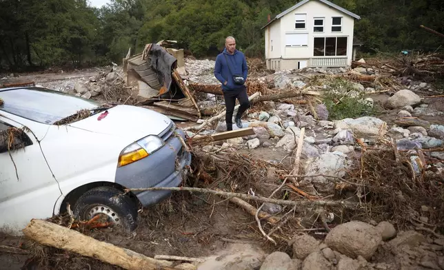 A man walks among a destroyed car and homes following a flooding in Buturovic Polje, Bosnia, Sunday, Oct. 6, 2024. (AP Photo/Armin Durgut)