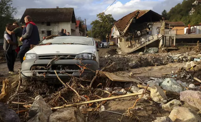 A destroyed car and a house are seen following a flooding in Buturovic Polje, Bosnia, Sunday, Oct. 6, 2024. (AP Photo/Armin Durgut)