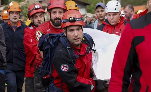 Members of the mountain rescue service carry a body of a person killed by a landslide in the flooded village of Donja Jablanica, Bosnia, Saturday, Oct. 5, 2024. (AP Photo/Armin Durgut)