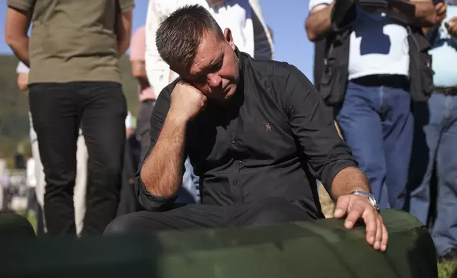 A person mourns over a coffin during the collective funeral for 19 victims of a landslide caused by recent floods in Jablanica, Bosnia, Tuesday, Oct. 15, 2024. (AP Photo/Armin Durgut)