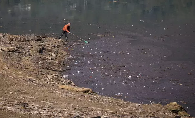 Dervis Gabela collects plastic waste from the shore after devastating floods and landslides put tons of waste in Jablanicko lake near Ostrozac, Bosnia, Sunday, Oct. 20, 2024. (AP Photo/Armin Durgut)