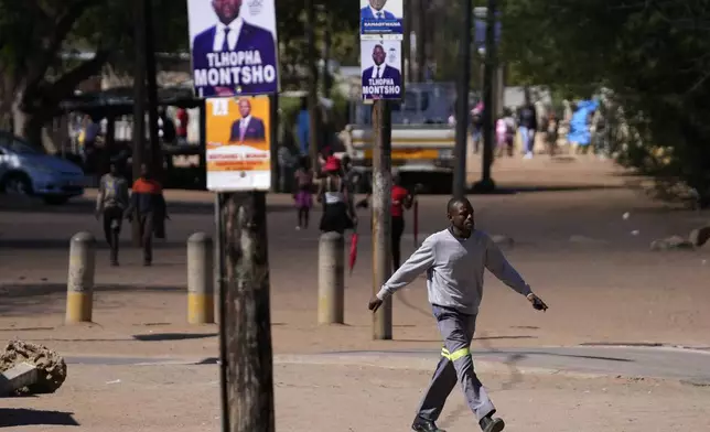 A man walks passes election posters, a day before elections in Gaborone, Botswana, Tuesday, Oct. 29, 2024. (AP Photo/Themba Hadebe)