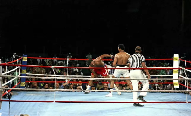 FILE - Challenger Muhammad Ali watches as defending world champion George Foreman struggles to keep his balance during the WBA/WBC championship bout in Kinshasa, Zaire, on Oct. 30, 1974. (AP Photo, File)