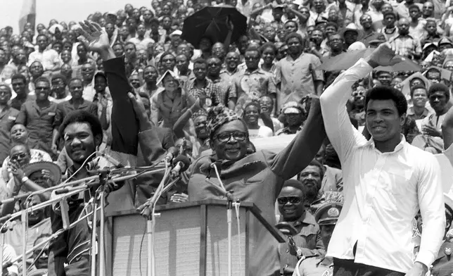 FILE - This is a Sept. 22, 1974 file photo of Zaire's President Mobutu Sese Seko, center, as he raises the arms of heavyweight champ George Foreman, left, and Muhammad Ali, right, in Kinshasa, Zaire. (AP Photo/Horst Faas, File)