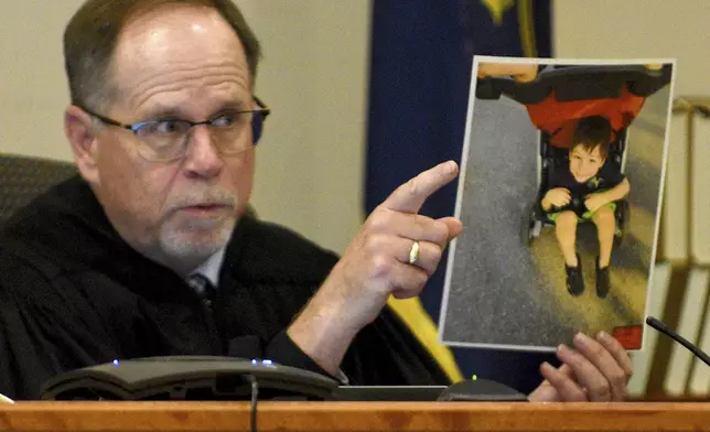 Superior Court Justice Charles Temple holds a photograph of Elijah Lewis as he explains his sentence at the hearing for Danielle Dauphinais at Hillsborough County Superior Court South in Nashua, N.H., on Friday, Oct. 25, 2024. (David Lane/Union Leader via AP, Pool)