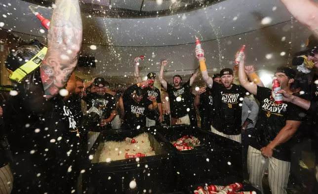 San Diego Padres players celebrate in the dugout after defeating the Atlanta Braves in Game 2 of an NL Wild Card Series baseball game Wednesday, Oct. 2, 2024, in San Diego. (AP Photo/Gregory Bull)