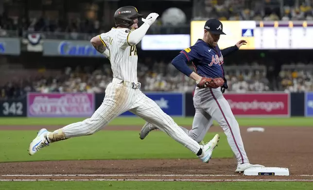 San Diego Padres' Jackson Merrill, left, is out at first base on a ground ball behind Atlanta Braves relief pitcher Aaron Bummer during the fourth inning in Game 1 of an NL Wild Card Series baseball game Tuesday, Oct. 1, 2024, in San Diego. (AP Photo/Gregory Bull)