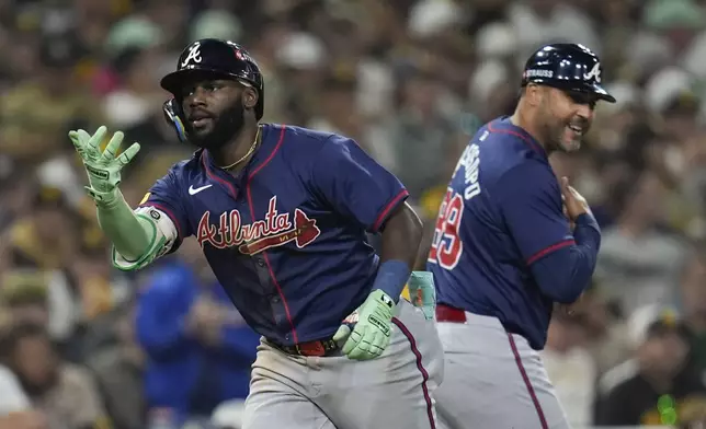 Atlanta Braves' Michael Harris II, left, celebrates with third base coach Matt Tuiasosopo after hitting a two-run home run during the eighth inning in Game 2 of an NL Wild Card Series baseball game against the San Diego Padres, Wednesday, Oct. 2, 2024, in San Diego. (AP Photo/Gregory Bull)