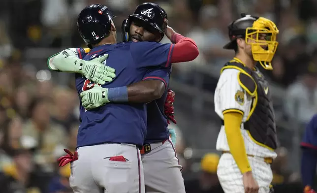 Atlanta Braves' Michael Harris II, center, hugs Orlando Arcia, left, after Harris' two-run home run during the eighth inning in Game 2 of an NL Wild Card Series baseball game against the San Diego Padres, Wednesday, Oct. 2, 2024, in San Diego. (AP Photo/Gregory Bull)