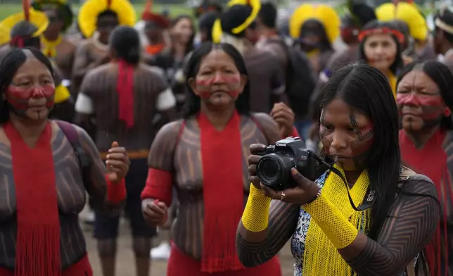 A Kayapo woman takes photos during a protest against a proposed constitutional amendment that threatens some Indigenous land rights, in Brasilia, Brazil, Wednesday, Oct. 30, 2024. (AP Photo/Eraldo Peres)