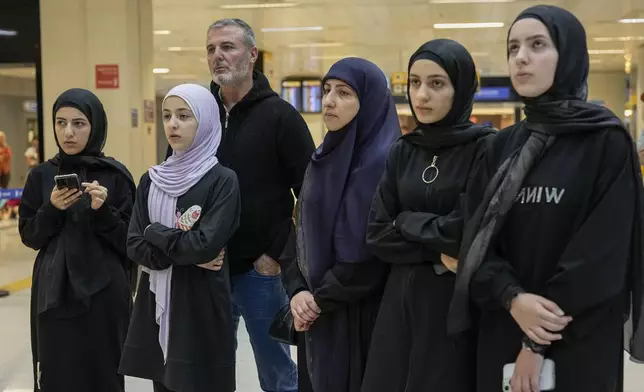 Lebanese citizen Ali Zeineddine, third from left, waits with family for his brother arriving from Lebanon at Sao Paulo International airport, after an Israeli air strike killed various members of their family, Thursday, Oct. 3, 2024. (AP Photo/Andre Penner)