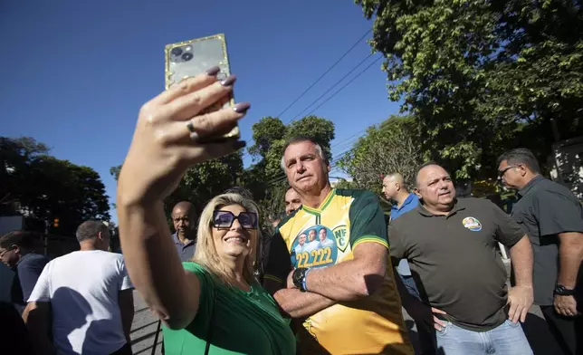 A supporter takes a selfie with former President Jair Bolsonaro as he accompanies Rio de Janeiro mayoral candidate Alexandre Ramagem during the municipal elections in Rio de Janeiro, Sunday, Oct. 6, 2024. (AP Photo/Bruna Prado)