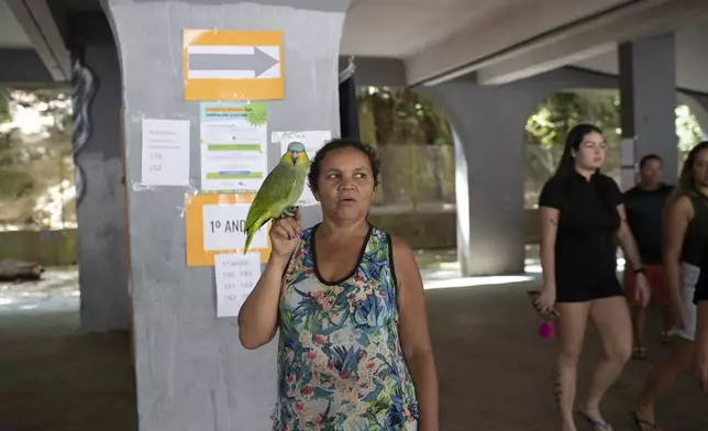 Tereza Domingos holds her parrot Noninho after voting in the municipal elections in the Rocinha community of Rio de Janeiro, Sunday, Oct. 6, 2024. (AP Photo/Bruna Prado)