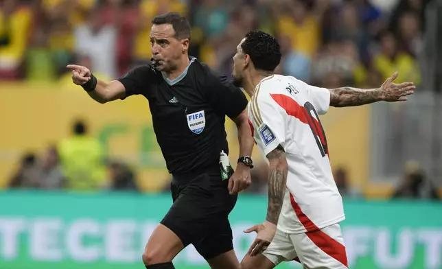 Referee Esteban Ostojich points to the penalty spot after a VAR review to grant Brazil a penalty during a qualifying soccer match for the FIFA World Cup 2026 against Peru at Mane Garrincha Stadium in Brasilia, Brazil, Tuesday, Oct. 15, 2024. (AP Photo/Eraldo Peres)